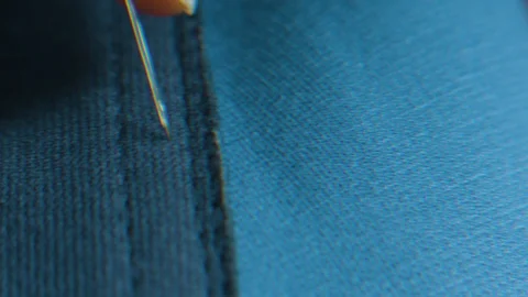 Extreme close up of needle inserted into blue fabric Stock Footage 124244031