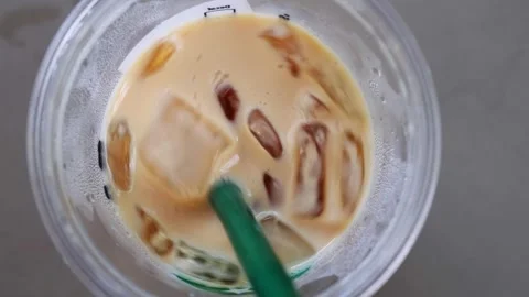 Extreme close-up overhead view of a refreshing iced latte coffee being stir.. Vídeos de archivo 348284533