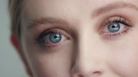 Extreme close up pan across young model's bright blue eyes looking into camera 스톡 동영상 193958643