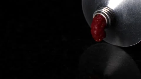 Extreme close up pressing out tomato paste, isolated black background Stock Footage 147346147