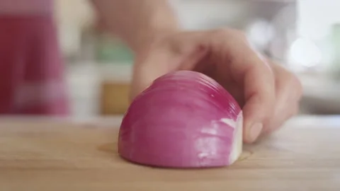Extreme close up of a red onion getting sliced into quarters Video stock 153289176