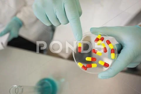Extreme close up of scientist holding a petri dish filled with pills Stock Photos