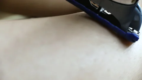 Extreme close-up of shaving machine shaving hair on young woman leg Stock-Footage 130818724