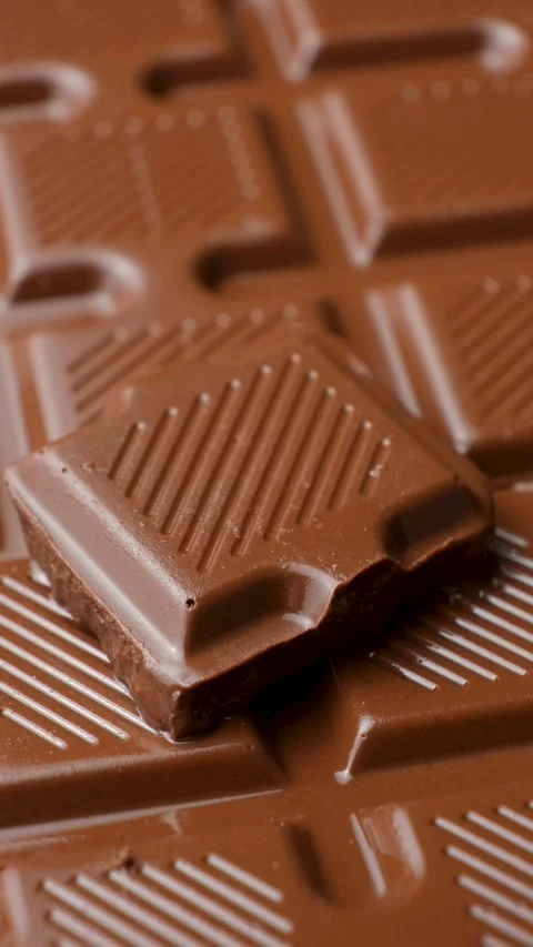 Extreme close up shot of chocolate chunk turning on chocolate bar surface Stock Footage 345660813