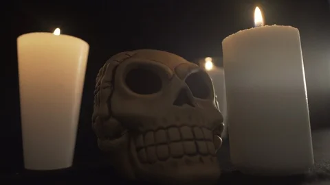 Extreme close up to a skull with three candles light up Stock Footage 96565111