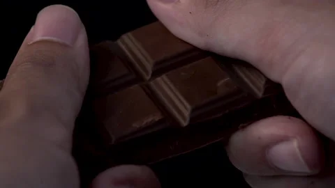 Extreme close up slow-motion breaking a chocolate bar , some piece of chocol Видео 136210073