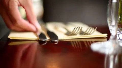 Extreme Close-Up of Someone Laying Out Knives and Forks on a Wooden Dining Table Stock Footage 44086155