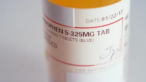 Extreme close-up of a spinning bottle of oxycodone pills label on white Stock-Footage 119090845
