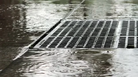 Extreme Close Up Storm Drain Grate with Flooded Water and Rain drops in a puddle Stock Footage 343476968