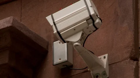 Extreme close up of surveillance camera facing building entrance, day. Stock-Footage 110805266