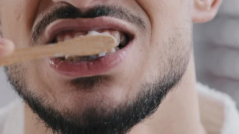 Extreme close-up unrecognizable bearded man brushing teeth with white paste 스톡 동영상 169704827