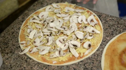 Extreme close up of unrecognizable man putting cheese topping on his pizza base Stock Footage 62554024