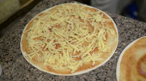 Extreme close up of unrecognizable man putting cheese topping on his pizza base Video stock 62554074