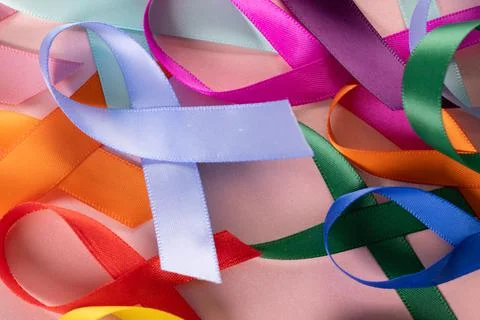 Extreme close-up of various multicolored awareness ribbons on pink background, Stock Photos
