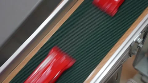 Extreme close view of a glossy sealed red pouch sliding along a dark green Stock Footage 342319373
