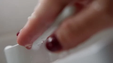 Extreme close-up of a white plastic measuring scoop and fingers with water Stock Footage 317590607