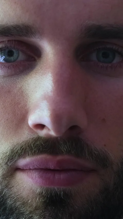 Extreme close-up of a young bearded man's face as he slowly opens his serene Stock Footage 345115465