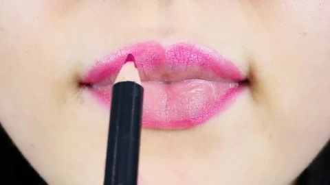 Extreme close-up of young woman's lips. Woman paints her lips with red lipstick. Видео 112956469