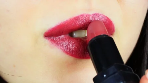 Extreme close-up of young woman's lips. Woman paints her lips with red lipstick. Vídeo Stock 112956526
