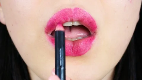 Extreme close-up of young woman's lips. Woman paints her lips with red lipstick. 動画素材 112956671