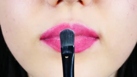 Extreme close-up of young woman's lips. Woman paints her lips with red lipstick. 動画素材 112956684