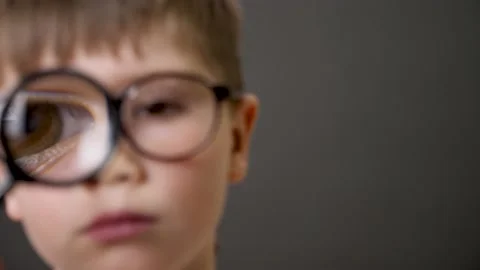 Extreme closeup eye looking through magnifying loupe. Big eye boy close up Stock Footage 153052367