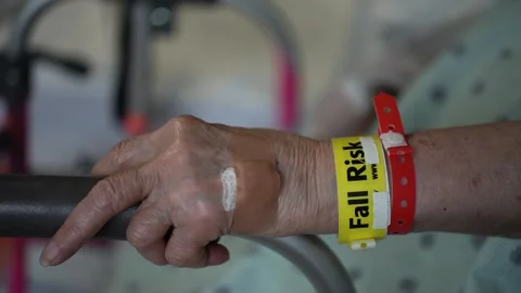 Extreme closeup of Fall Risk wristband on elderly patient in hospital as she 스톡 동영상 287572129