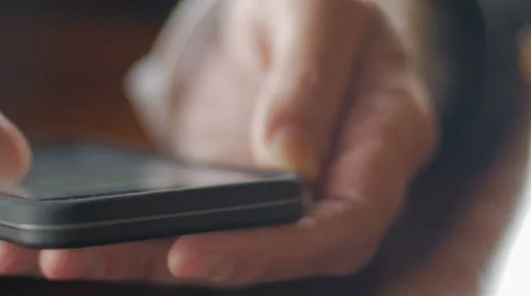 Extreme closeup of mans hands scrolling through mobile phone - dolly Stock Footage 65338322