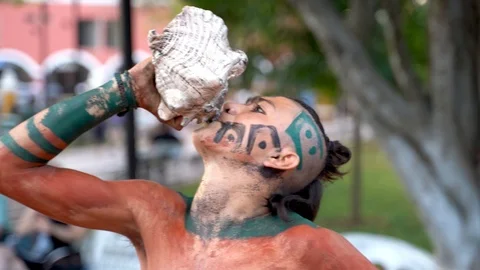 Extreme closeup of a Mayan or Aztec dancer playing a conch shell during a Stock Footage 126990986