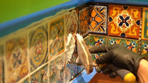 Extreme closeup of a spatula float applying grout to colorful tiles. Stock Footage 101434794