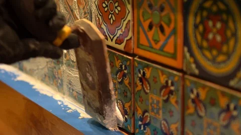 Extreme closeup of spatula float pressing wet grout in between colorful Stock Footage 101434724