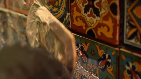 Extreme closeup of spatula float pressing wet grout in between colorful Stock Footage 101434765