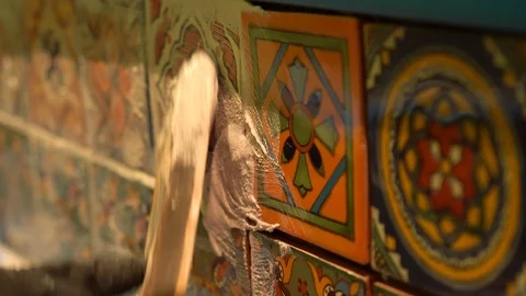 Extreme closeup of spatula float pressing wet grout in between colorful Stock Footage 101434772