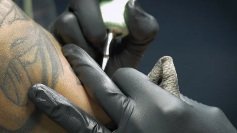 Extreme Closeup of a Tattoo Artist Using a Needle to Ink a Client  - 4k Stock Footage 97950663