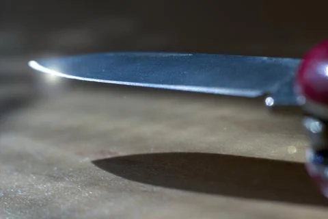 Extreme focus of pointy sharp knife with light flare at the edge. Shiny metal Stock Photos