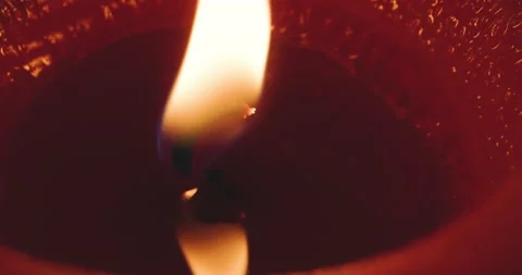 Extreme macro close-up of flickering fire on wick of red candle Stock Footage 228675923