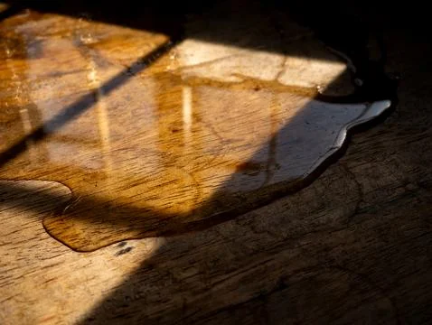 Extreme macro close-up of melted ice water puddle edge on aged rustic woode.. Stock-Fotos