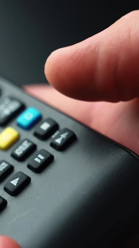 Extreme macro of a fingertip pressing the fast-forward button on a TV remote Stock Footage 329480151