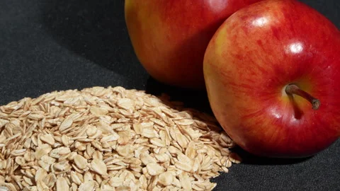 Extreme Macro Rotating Rolled Oats and Two Red Apples on Black. Видео 333044252