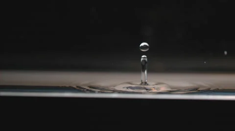 Extreme slow motion, drop falls to calm surface, splashing in concentric ripples Stock Footage 63830240