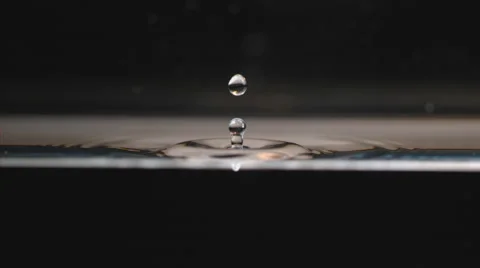 Extreme slow motion drop falls in water, splashing in geometric ripples on black Stock Footage 63836168