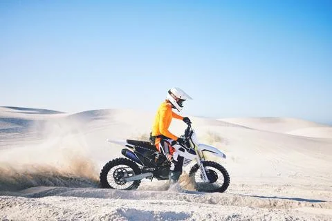 Extreme sport, motorcycle and athlete with sand by wheels with pride, skill and Stock Photos