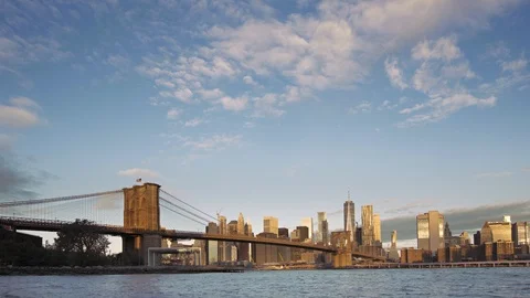 Extreme wide angle of Brooklyn Bridge to Lower Manhattan dwarfed by sky; morning Stock Footage