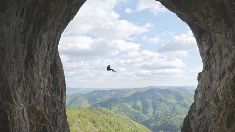 Extreme Wide Shot of Climber Rappelling Through Massive Cave Portal Stock Footage 345632442