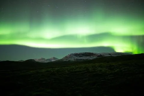 Extremely bright aurora borealis over snowy moutains, Iceland Stock Photos