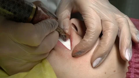 Extremely close-up cosmetic procedures permanent makeup lips. The cosmetologist Video stock 98095170