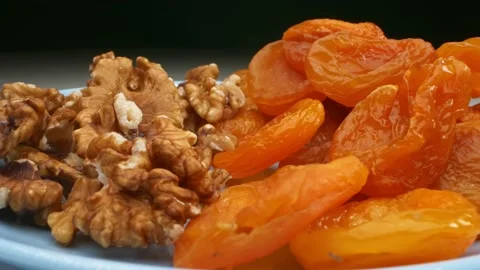 Extremely close-up, detailed. walnut kernels and dried apricots on a blue plate Stock Footage 147070256