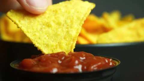 Extremely close up nacho chip dipping into tomato sauce Video stock 243433975