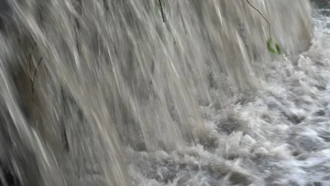 Extremely close-up of the rapid flow of muddy bubbling water rushing Stock Footage 111718134