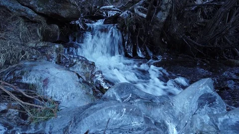 A extremely close up shot of iced water at the shore of a tiny creeek on Stock Footage 124297442